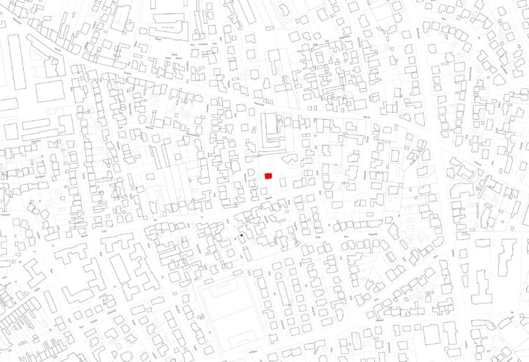 Une carte de la ville en noir et blanc avec différents contours de bâtiments ; un simple carré rouge près du centre met en évidence un bâtiment spécifique parmi l